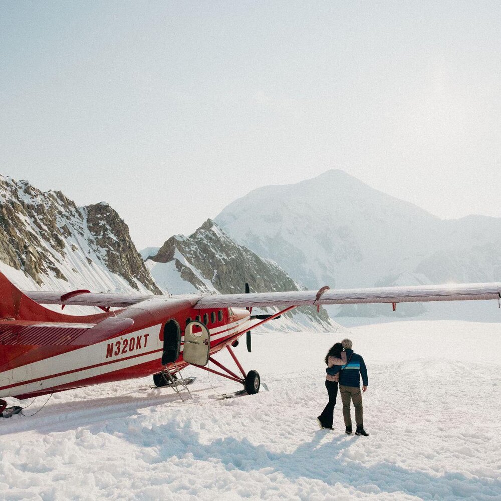 Guests standing beside a ski plane after landing on a glacier near Denali